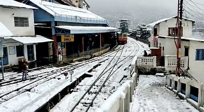 A train treads on the snow-covered railway track amid heavy snowfall, in Shimla on Sunday