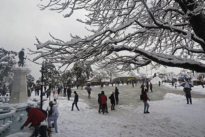 Tourists enjoy snow-covered Ridge after a fresh snowfall, in Shimla on Sunday.