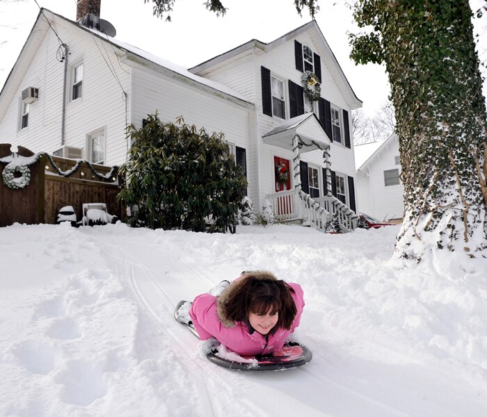 Victoria Monteleone, 8, enjoys a ride down the snow-covered hill in front of her home in East Norwich, New York after a blizzard hit the Long Island area throughout the night on December 20, 2009. (AP Photo)