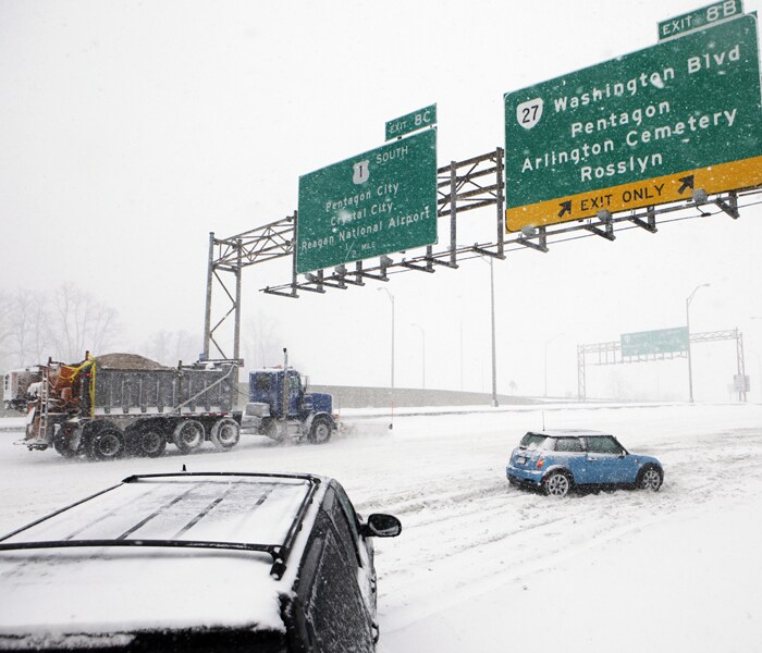 A snow plow truck works to clear the roadway as snow continues to fall and vehicles become trapped along Interstate 395 in Arlington, Virginia. (AP Photo)