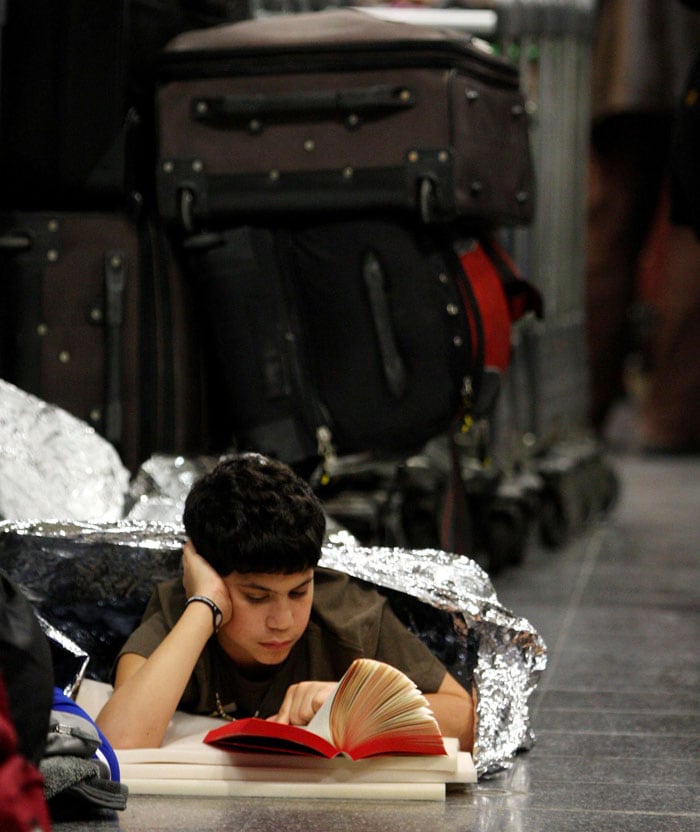 A young boy reads his book as passengers wait in the departures area of Terminal 3 at London's Heathrow Airport as travel chaos continues due to the adverse weather Tuesday Dec. 21 2010. Major delays and cancellations persisted Tuesday at European airports including London's Heathrow, and on the Eurostar train link, leaving thousands stranded across Europe as Christmas approached. Predicted snowfall at Heathrow did not materialize overnight, allowing cleanup crews to intensify their work, but more than half the flights at Europe's busiest international hub were expected to be canceled.(Photo courtesy: AP)