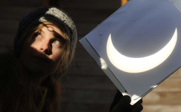 An enthusiast uses a projection shield to see the partial solar eclipse as visible in Czech capital Prague on January 4, 2011. In the culminating phase, up to 80 percent of the solar disc was obscured by the silhouette of the Moon passing between it and the Earth. (AP Photo)