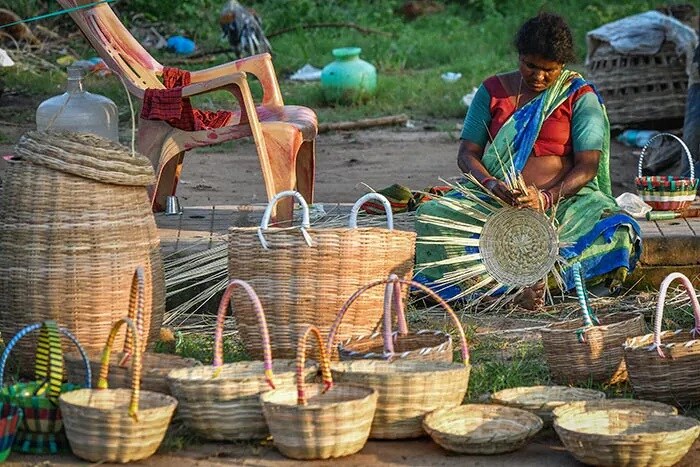 बेंगलुरु में सड़क के किनारे एक महिला गन्ने की टोकरी की बुनाई करते हुए.