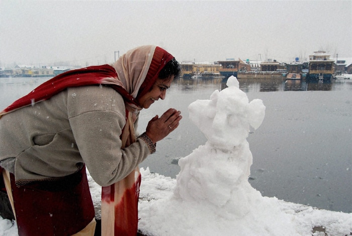 A woman tourist  prays before a snow idol of Lord Ganesh on the banks of Dal Lake in Srinagar on Thursday. (PTI Photo)