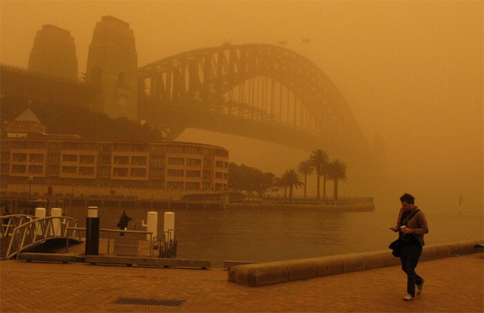 <strong>Shrouded in dust:</strong> A man walks to work past an almost unseen Sydney Harbour Bridge during a dust storm on September 23, 2009, in Sydney, Australia.<br />
<br />
Flights were diverted and ferries cancelled as a blanket of red dust shrouded most of Sydney after the weather system moved in from central Australia. <em>(AP)</em>