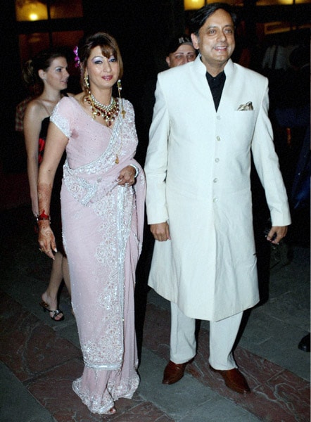 The couple back after their Spain honeymoon, walked hand in hand. Shashi Tharoor in white Indo-Western <i>sherwani</i> and Sunanda in fluorescent pink saree, looked as lovestruck as ever, say onlookers. (PTI Photo)