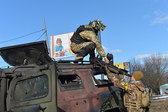 An Ukrainian fighter takes the automatic grenade launcher from a destroyed Russian infantry mobility vehicle after the fight in Kharkiv.