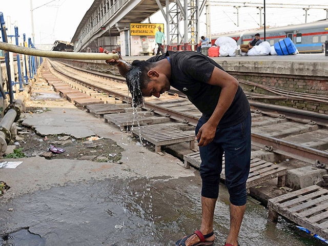 गर्मी के मौसम में भीषण गर्मी से राहत के लिए रेलवे स्टेशन पर सिर पर पानी छिड़कता हुआ एक व्यक्ति. (फोटो- पीटीआई)