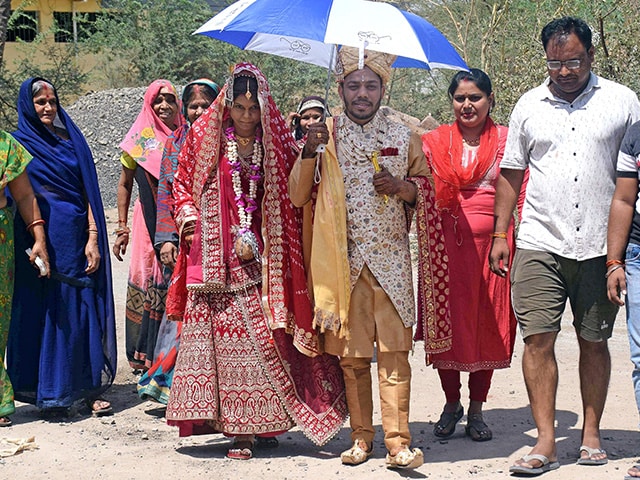 एक नवविवाहित जोड़ा भीषण गर्मी से खुद को बचाने के लिए छतरी के नीचे शरण लिए हुए है. (फोटो- पीटीआई)