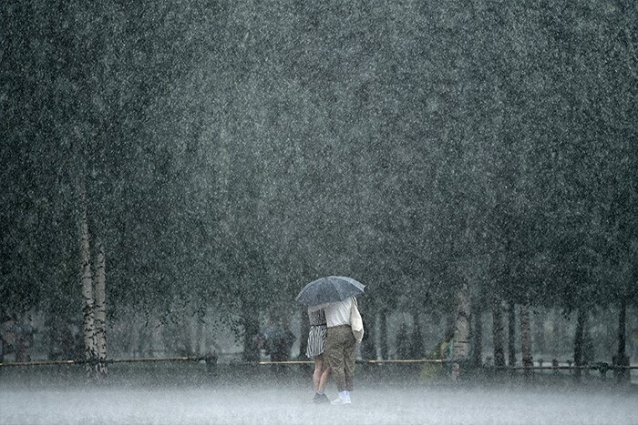 A couple stand under a rain shower in downtown Moscow, Russia.