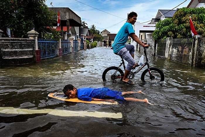 A child uses a surfboard in floodwaters following heavy rain at a residential area of Ajun on the outskirts of Banda Aceh, Indonesia.