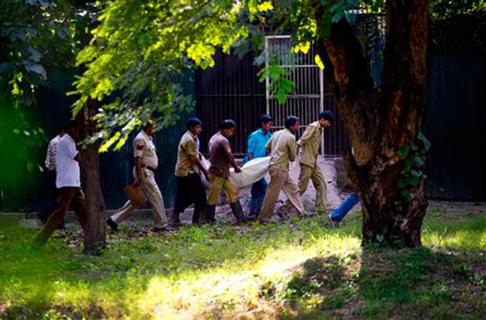 Police and Delhi Zoo officials carry the man's body from the Tiger's enclosure. (Associated Press)