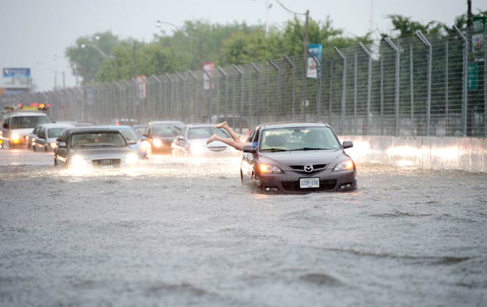 A woman dove head-first through the window of her marooned car before wading away in the thigh-deep currents.