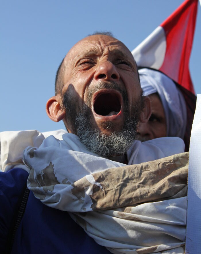 Families of victims who died in the Revolution gathered outside are demanding Mubarak's death penalty. A victim carries his 8 year old son's bloodstained vest who died last January.