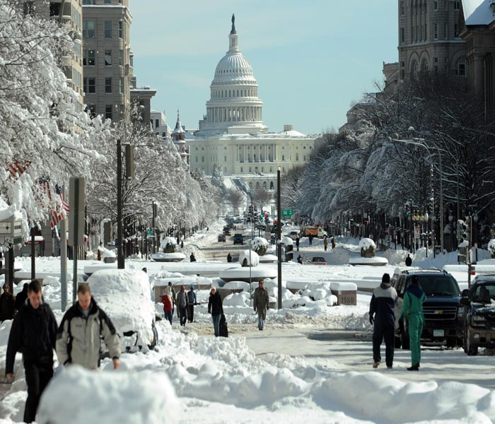 Commuters make their way on a snow covered street in Washington,DC.<br><br>Hundreds of emergency crews battled to clear snow-clogged roads and restore power to thousands of homes across the US east coast before a new storm hits, aided by some welcome winter sun.(AFP Photo)