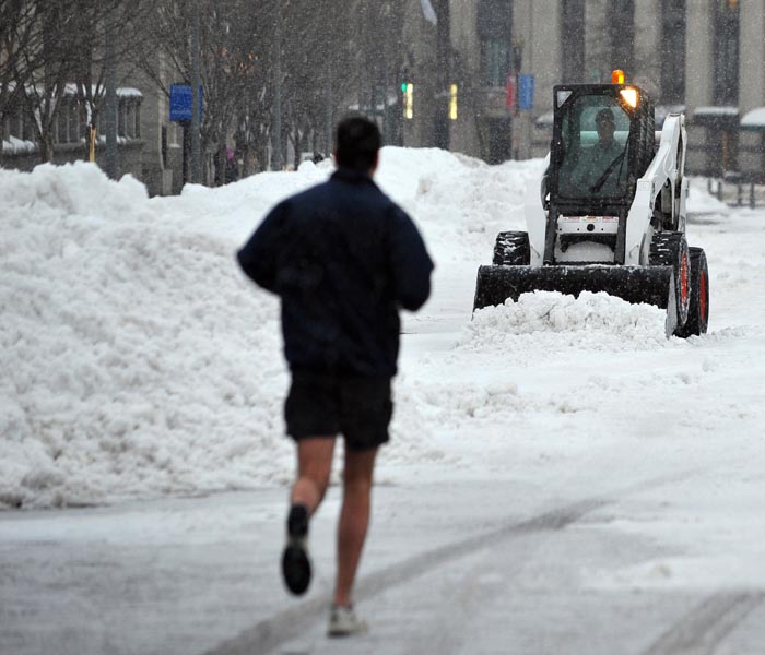 Snow is cleared from Pennsylvania Avenue as a runner passes by in front of the White House in Washington, DC.(AFP Photo)