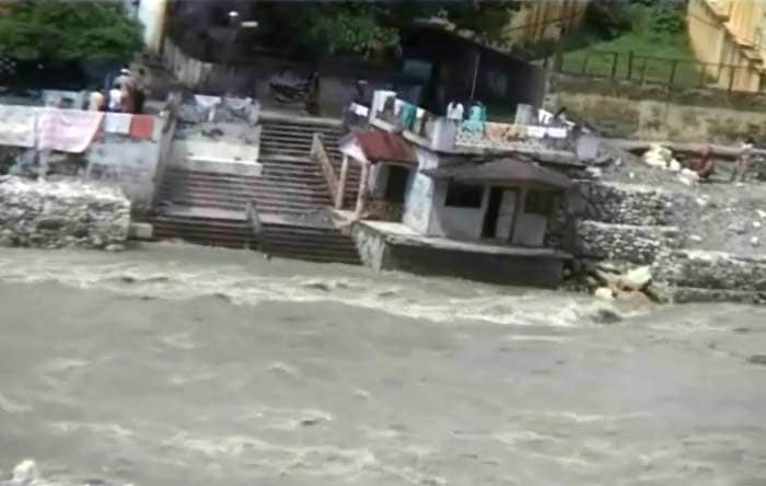 Swollen by the heavy rainfall a river flows dangerously close to a human settlement threatening the buildings on the riverside