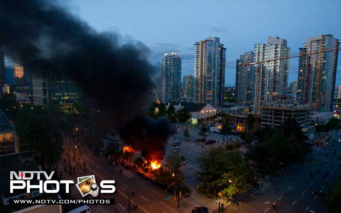 Smoke plumes rise from police cars set on fire following the Vancouver Canucks being defeated by the Boston Bruins in the NHL Stanley Cup Final in Vancouver, British Columbia. (AP Photo)