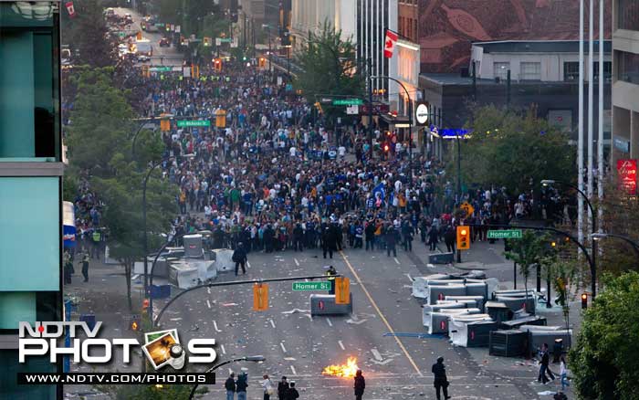 Revelers retreat as a police flash bang goes off in Vancouver. (AP Photo)