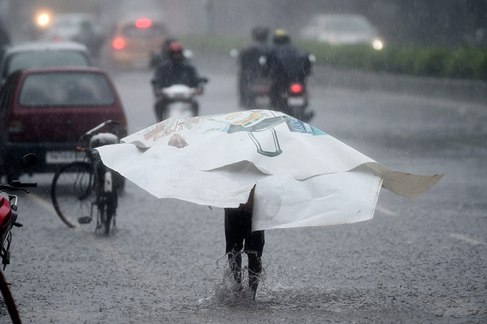 A person wades through road filled with water during heavy rainfall as cyclone Vardah made landfall near Chennai coast on Monday. (PTI Photo)