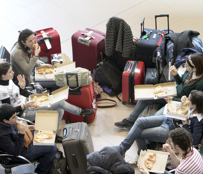 Travelers have snacks by their luggage at the Henri Coanda airport in Bucharest, Romania, shortly before the country closed all of its airspace on Saturday, April 17, 2010. (AP Photo)