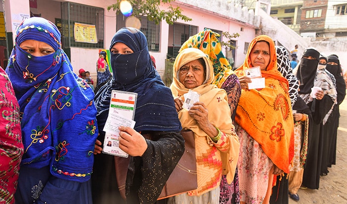 मध्य प्रदेश विधानसभा चुनाव के लिए वोट डालने के लिए मतदान केंद्र पर कतार में इंतजार करते समय मतदाता अपना पहचान पत्र दिखाते हुए. फोटो: पीटीआई