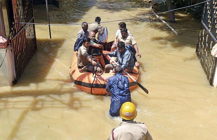 सोमवार को बेंगलुरु में लगातार बारिश के बाद क्षेत्र आंशिक रूप से जलमग्न होने के बाद एक इलाके के निवासियों को अग्निशामकों द्वारा निकाला गया(फोटो पीटीआई)