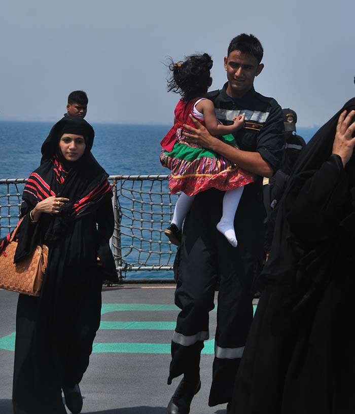 A Navy officer carries a child while escorting the mother on the INS Mumbai during a rescue and evacuation operation in Yemen's Aden. Photo Courtesy: Indian Navy