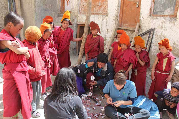 Hose and Kate are surrounded by curious little monks as they meticulously fix the wires on the bulb sockets.