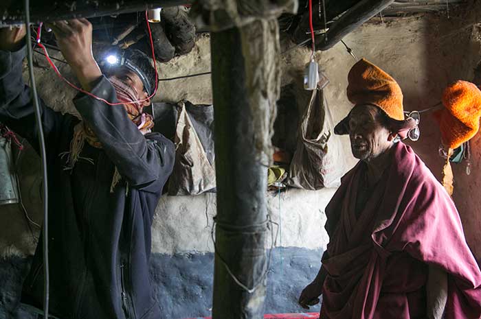 The monks and the team were all super excited about the installation. Here, a lama makes an attempt at wiring the bulb socket to the ceiling in the lobby.