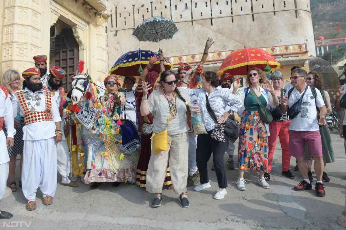 Bundi Festival 2024 Pictures: बूंदी महोत्सव के दूसरे दिन भी विविध मनोहारी कार्यक्रमों का दौर जारी रहा. सुखमहल में सुरम्य प्राकृतिक छटा के बीच देशी विदेशी पावणों की देशी व्यंजनों से मनुहार की गई. अतिरिक्त जिला कलेक्टर सुदर्शन सिंह तोमर, मुख्य कार्यकारी अधिकारी रवि वर्मा, नगर परिषद सभापति सरोज अग्रवाल सहित जिला प्रशासन के अन्य अधिकारियों एवं गणमान्य नागरिकों ने मेहमानों की खातिरदारी करते हुए उन्हें हाड़ौती के पसंदीदा व्यंजन कत्त बाफले से सत्कार किया. कार्यक्रमें पावणों को साफे बांधे गए. तिलक किया.