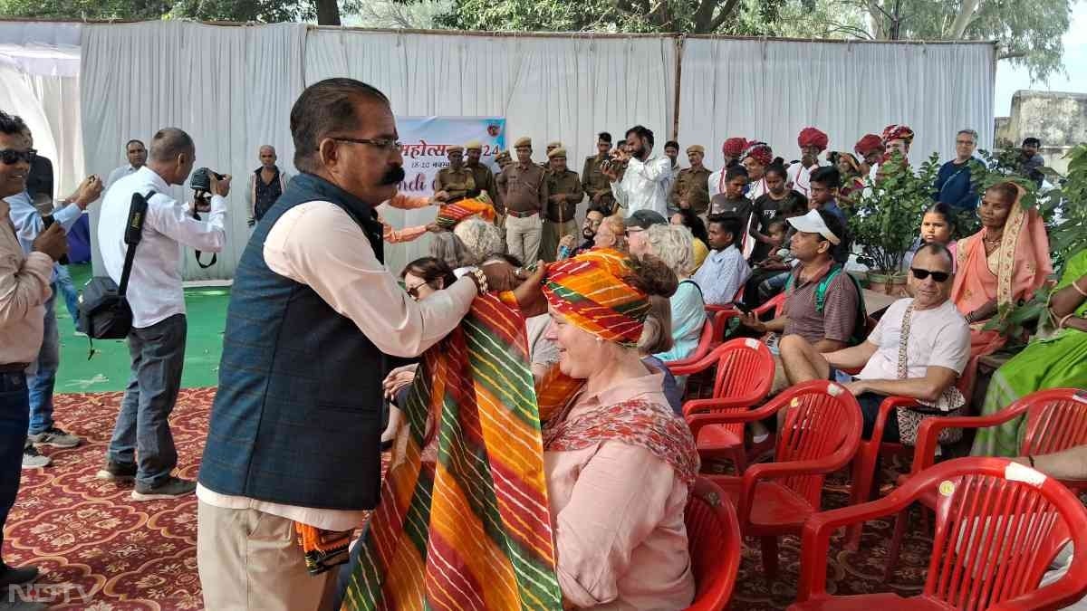 बूंदी महोत्सव में विदेश से आई महिला सैलानी को राजस्थानी साफा पहंचाते आयोजक सदस्य.