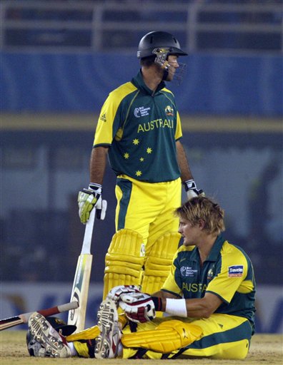 Australia's Shane Watson sits on the pitch after getting leg cramps as captain Ricky Ponting looks for help from the dressing room during the one day international cricket match for the ICC Champions Trophy in Mohali on Sunday. ICC CT Ind-Aus