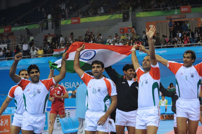 The Indian team carry their national flag on a victory lap after beating Iran in the kabaddi men's final match at the 16th Asian Games in Guangzhou. India beat Iran 28-16 for the gold medal. (AFP Photo)