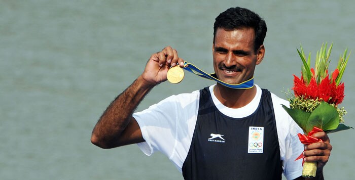 Barjang Lal Takhar of India celebrates on the podium during the medals ceremony for the men's single sculls rowing final during the 16th Asian Games in Guangzhou.  India won gold ahead of Taiwan for silver and Iraq for bronze. (AFP Photo)
