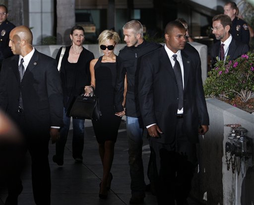 Beckham holding his wife's hand Victoria surround by bodyguards and police. Beckhams arrive in LA