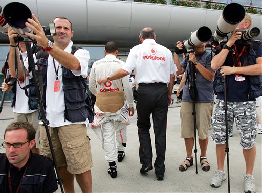 McLaren-Mercedes team director Ron Dennis, right, and British driver Lewis Hamilton walk together past still photographers toward their team's garage for the practice session. Hamilton awaits verdict