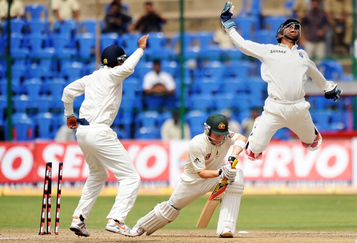 Mahendra Singh Dhoni jumps in the air after stumping Michael Clarke as Cheteshwar Pujara celebrates during the fourth day of the second Test between India and Australia at M. Chinnaswamy Stadium in Bangalore. (AFP Photo) IND vs AUS: 2nd Test, Day 4
