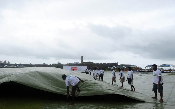 Ground staff pull a tarp to cover the ground as rain delays the start of the second day of the first Test match between Sri Lanka and India in Galle. (AFP Photo) India vs SL: 1st Test, Day 2