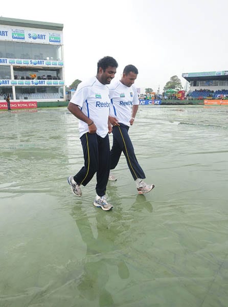 Sri Lankan cricketer Muttiah Muralitharan and Thilan Samaraweera inspect the pitch following rain that delayed the start of the second day of the first Test match between Sri Lanka and India in Galle. (AFP Photo) India vs SL: 1st Test, Day 2