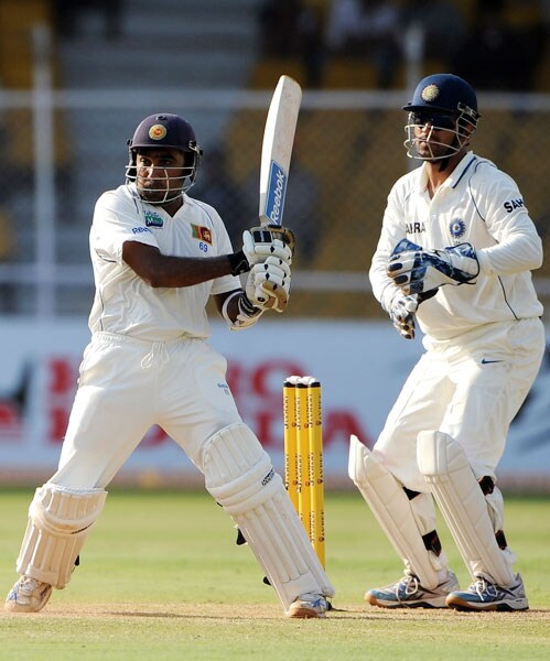 Mahela Jayawardene plays a shot as Mahendra Singh Dhoni looks on during the third day of the first Test match between India and Sri Lanka at the Motera stadium in Ahmedabad. (AFP Photo) India vs SL: 1st Test, Day 3