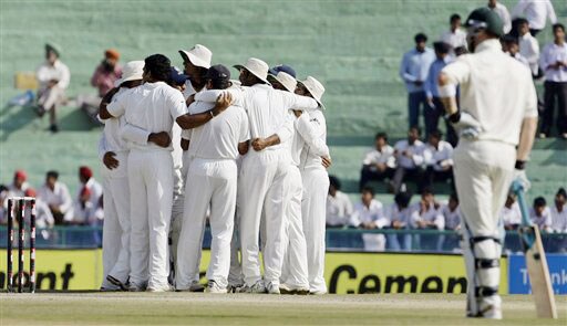 Michael Clarke looks on as Indian players huddle at the fall of Brett Lee's wicket during the final day of the second Test between India and Australia in Mohali. India vs Australia: 2nd Test, Day 5