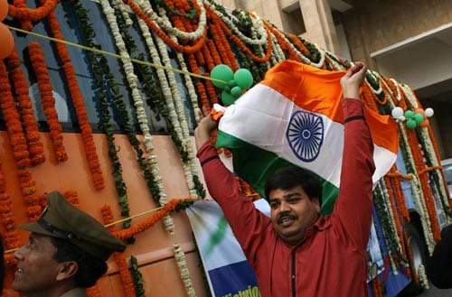 An Indian supporter waves the national flag as cricketers journey from a hotel in a garlanded bus towards a welcome ceremony in New Delhi on March 6, 2008. The champions are back