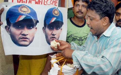 A fans offers sweets to a poster of cricketer Sourav Ganguly after his selection for the first two Tests against Australia in Kolkata. Team selection for Australia series