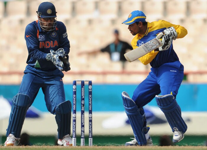 Mahendra Singh Dhoni (L) looks on as Sri Lankan cricketer Tillakaratne Dilshan plays a shot during the ICC World Twenty20 Super Eight match between Sri Lanka and India at the Beausejour Cricket Ground. (AFP Photo) WT20: Ind vs SL
